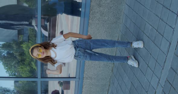 Pretty Young Girl Dancing in Stylish Look Outdoors at Urban Glassy Building