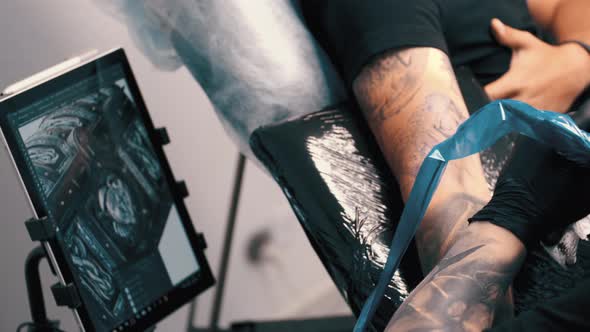 Male Tattoo Artist Tattooing a Client