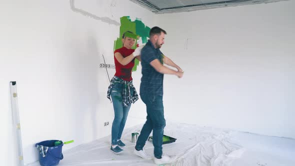 Cheerful Family Dances Painting White Wall in Modern Room