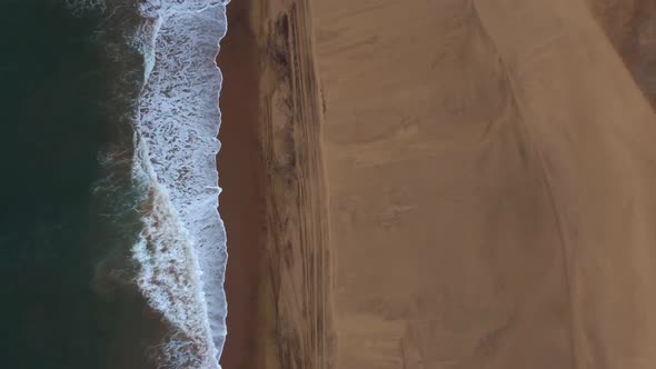 Birds eye drone shot of Sandwich Harbour in Namibia - drone is ascending where desert meets the ocea