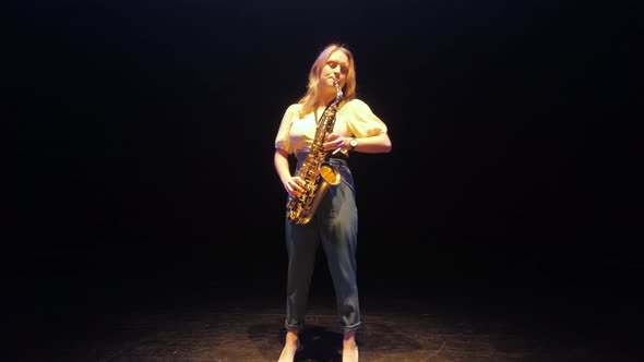 Female Saxophonist Playing Solo on Saxophone on Stage Under Lights