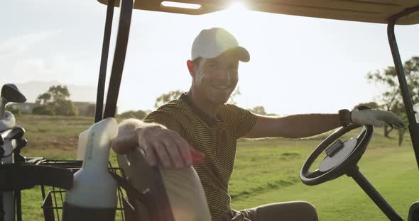 Caucasian male golfers into a golf buggy