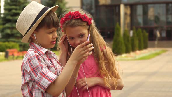 Little Children Watch Something on Smartphone Outdoors