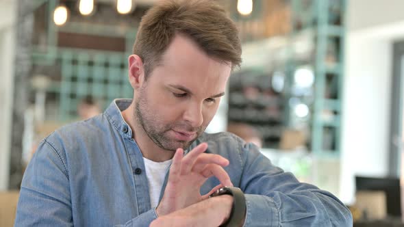 Portrait of Curious Casual Man Using Smart Watch 