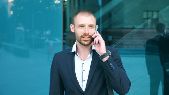 Portrait of Handsome Businessman Talking on Phone Near Office. Young Business Man Speaking