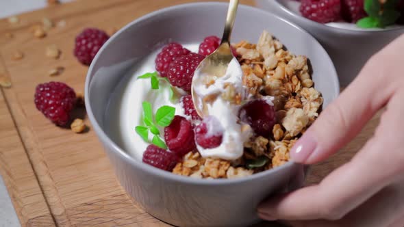 Breakfast muesli with yogurt and raspberries in a bowl.