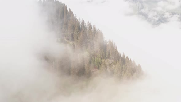 Aerial of mountain top rising over bright clouds