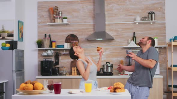 Carefree Couple Dancing and Singing in Kitchen