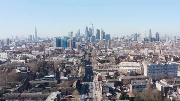 Dolly forward drone shot towards city of London skyscraper cluster over Whitechapel road