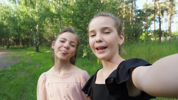 Couple of Girls Makes Selfie Grimacing in Park Closeup