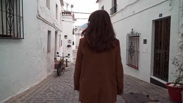 Zoom in Gimbal Shot of Woman Walking in Narrow White Street in Mijas