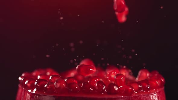 Pomegranate Grains Falling on Surface of Half Pomegranate in Slow Motion