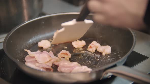 Restaurant Cooking  Chef Roasts Bacon Pieces in a Frying Pan