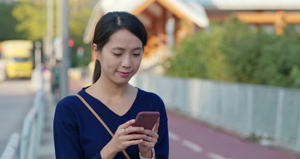 Young woman look at the smart phone at the street