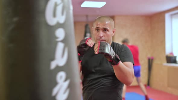 A young MMA fighter trains on a punching bag, practicing punches