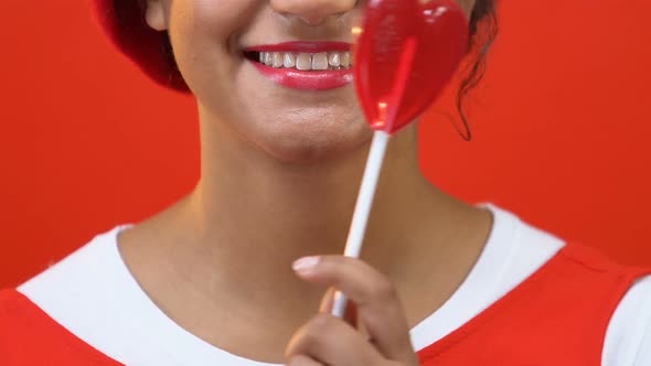 Afro-American Young Woman Holding Heart-Shaped Candy Front of Mouth, Love Symbol