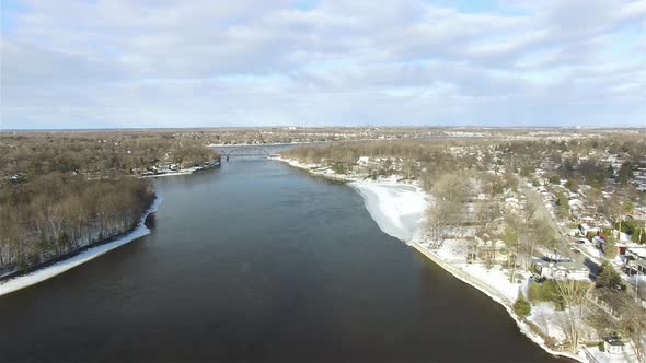 Aerial view of a river flowing through a town, with melting snow, on a sunny day