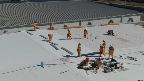 People Waterproofing an Industrial Rooftop