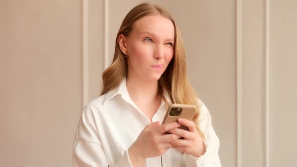 Young woman pensively thinks having doubts and using a mobile phone, chatting in social media