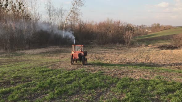 Wide Shot of Tractor Riding on Spring Field on Sunny Day