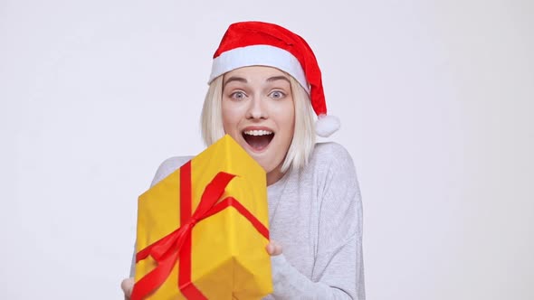 Young Beautiful Blonde Girl in Christmas Hat Suddenly Getting Gift Box White Background Slow Motion