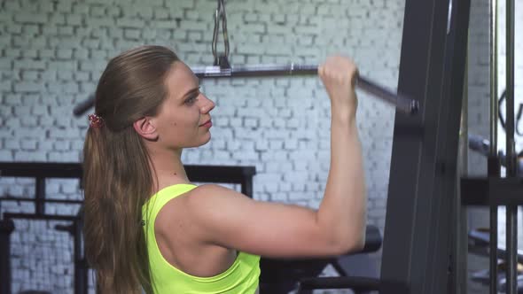 Attractive Athletic Woman Exercising on Lat Pulldown Cable Gym Machine