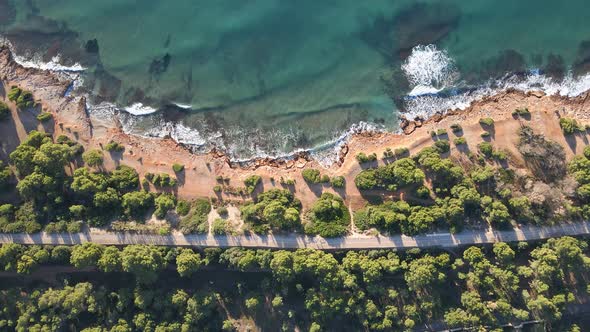 Aerial overhead image of the rocky coast in a place of the blue Mediterranean sea with sunrise light