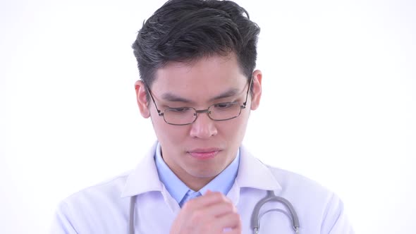 Face of Stressed Young Asian Man Doctor Thinking and Looking Down