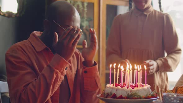 Joyous Man Blowing Candles on Birthday Cake at Home Celebration