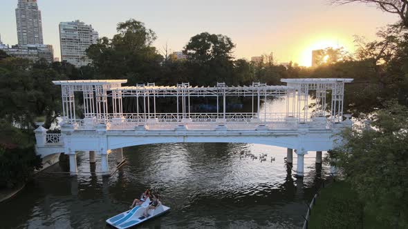 Static shot of tourists paddling paddleboat through bridge followed by a flock of waterfowls in tran