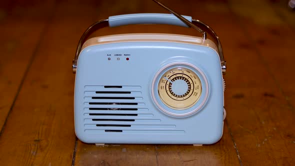 An old blue radio with a males mans hand pressing the buttons on the radio