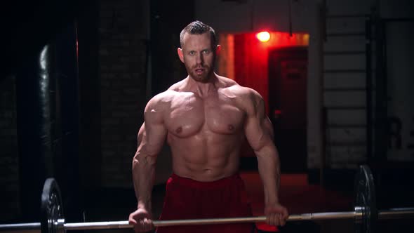 Tough Man Covered in Sweat Doing Exercises - Pulling Up a Heavy Bar with an Effort