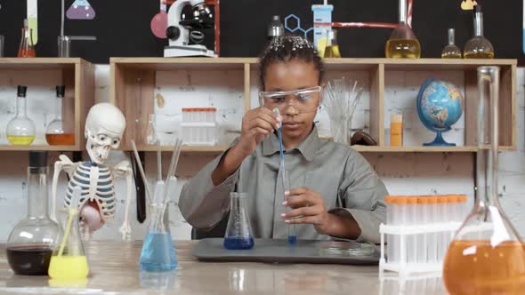 Laboratory Experience in a Chemistry Lesson African Girl in Protective Glasses Pours a Blue Liquid