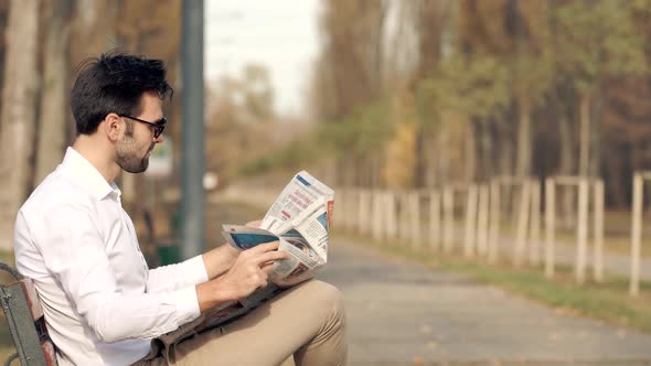 Businessman Relaxing And Reading Fresh Newspaper. Man Sitting On Bench And Reading Newspaper.