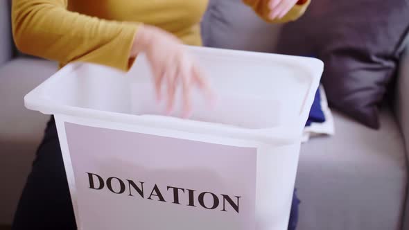 Detail of  Woman selecting clothes for donation. Clothing donations concept.