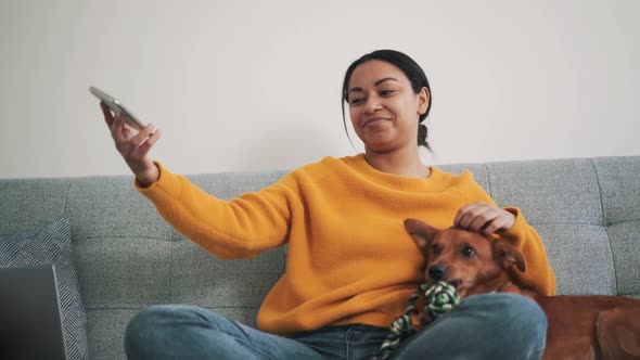 Smiling African woman making selfie with her dog