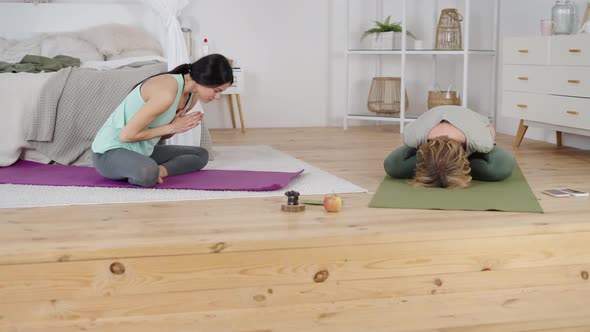 Yoga Trainer Exercising with Young Woman During Private Class at Home