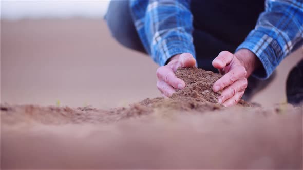 Farmer Examining Organic Soil in Hands, Farmer Touching Dirt in Agriculture Field