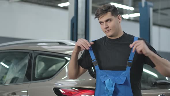 Confident Handsome Repairman Posing in Car Workshop Indoors