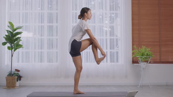 In sportswear, an Asian lady works out. Natarajasana,