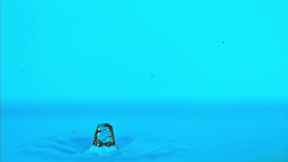 Super Slow Motion Water Falls on the Table on a Blue Background