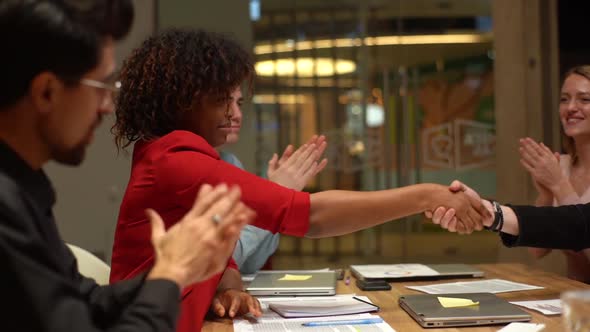 Side View of Shaking Hands of AfricanAmerican Businesswoman with Unrecognizable Business Partner As