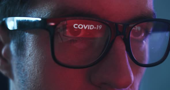 Closeup of Man Working at a Computer Reflected in Glasses Warning of COVID 19