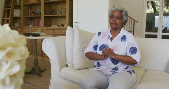 Worried african american senior woman sitting on the couch at home