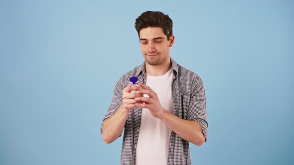 Young Man in Casual Outfit is Holding Bottle of Medicine Takes One Pill and Smiling