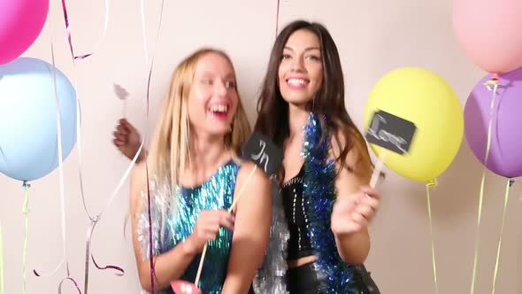 Cheerful friends dancing with a sign in love in party photo booth