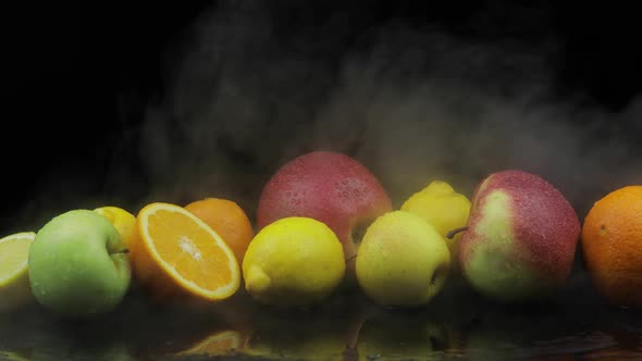 Tropical Lemon, Orange, Apple in Cold Ice Clouds of Fog Smoke on Dark Background