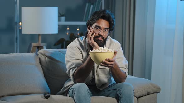 Upset Sad Bored Arab Man Tired Indian Male with Beard Sits at Home Evening Watching Boring TV