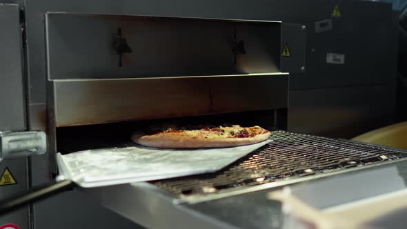 The Process Of Taking Out The Finished Pizza From A Red Hot Industrial Oven. The Process Of Cooking