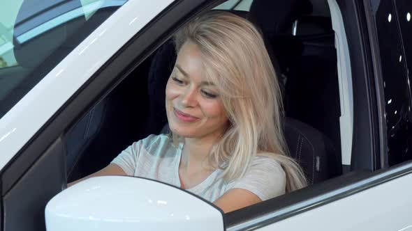 Gorgeous Woman Sitting in a Car, Looking in the Side Mirror